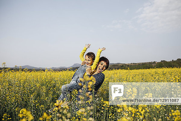 Spain  portrait of happy mother and her little son up standing in rape field