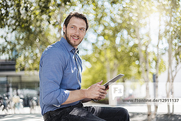 Smiling businessman using tablet outdoors in the nature