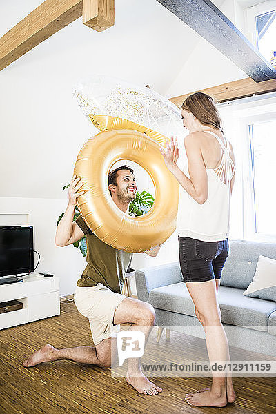 Smiling man looking at girlfriend through large inflatble ring at home