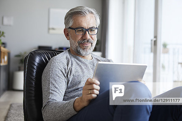 Portrait of mature man using tablet at home
