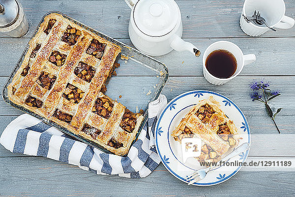 Homemade apple tart on plate and cup of black tea