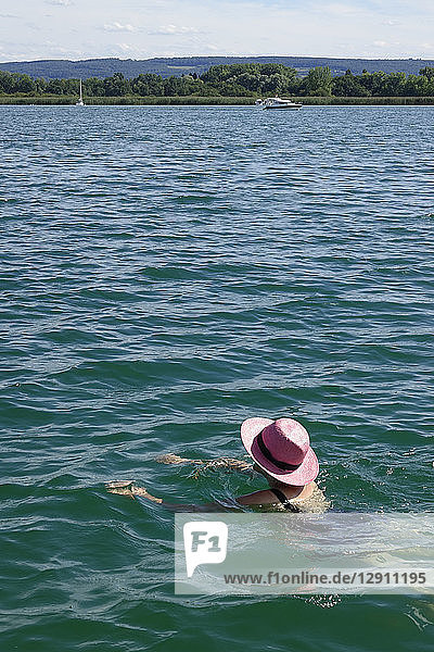 Woman wearing pink hat swimming in a lake