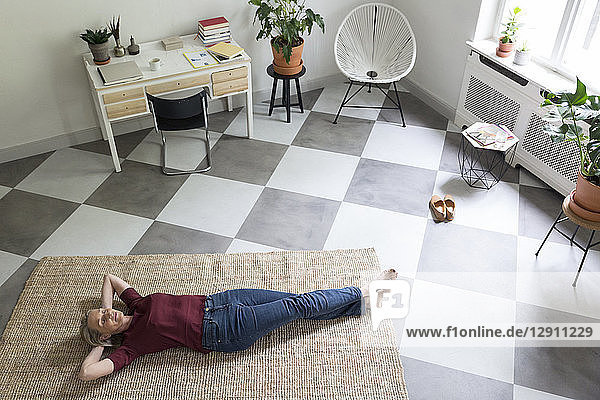 Relaxed mature woman lying on the floor at home