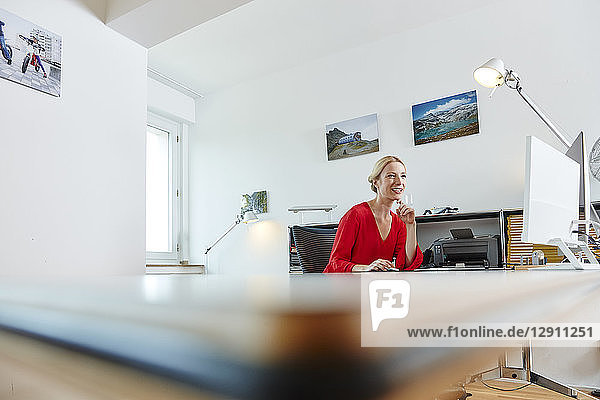 Smiling young woman working on computer at desk in office