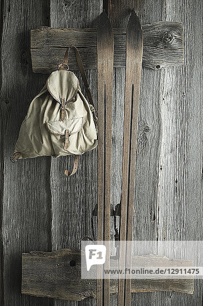 Wooden ski and old backpack on a rustic wooden wall