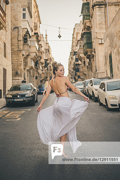 Teenage girl weraing long skirt and bikini top  posing in the street