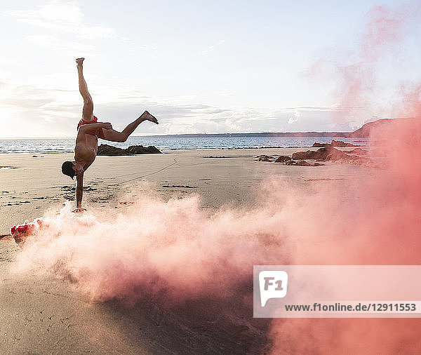 Man doing movement training at the beach with red smoke