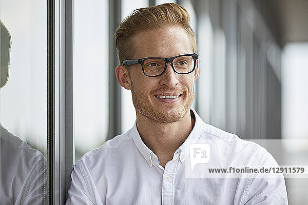 Portrait of smiling businessman leaning against window