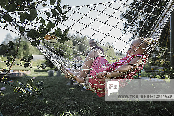 Little girl relaxing in hammock in garden