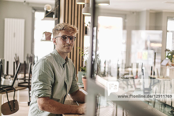 Young business owner sitting in his coffee shop  using laptop