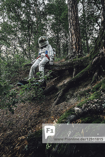 Spaceman exploring nature  sitting on tree roots
