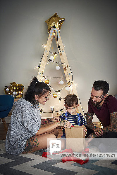 Boy opening Christmas present with his parents at home