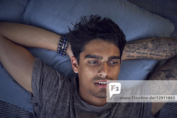 Young man with tattoo  relaxing on cushion