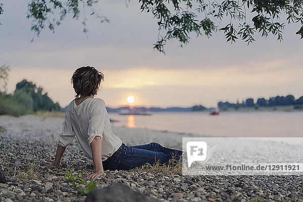 Woman sitting at the river  watching sunset