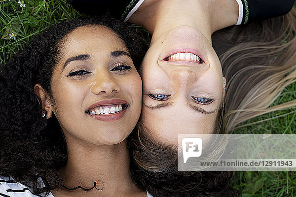 Two girlfriends relaxing in a park  lying on grass