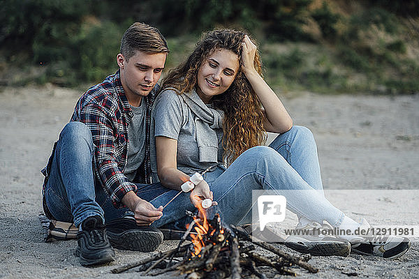 Romantic couple sitting at a campfire at he riverside