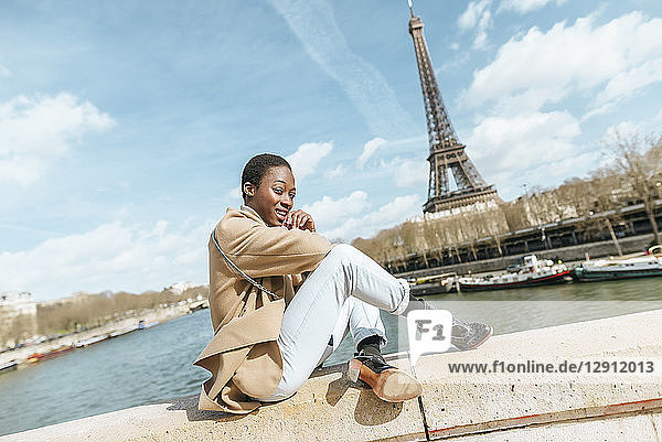 France  Paris  Woman sitting on bridge over the river Seine with the Eiffel tower in the background