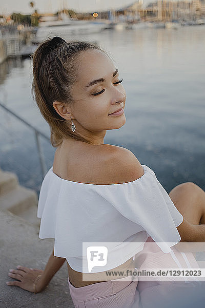 Portrait of a beautiful young woman  sitting at the harbour of Barcelona  Spain