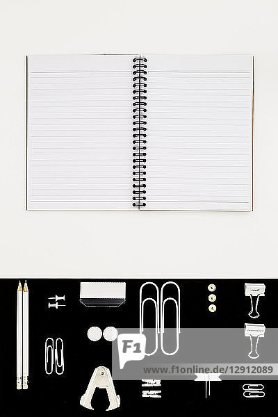 White office utensils on black background and notepad on whilte background
