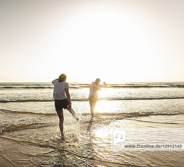 Young couple having fun at the beach  splashing water in the sea