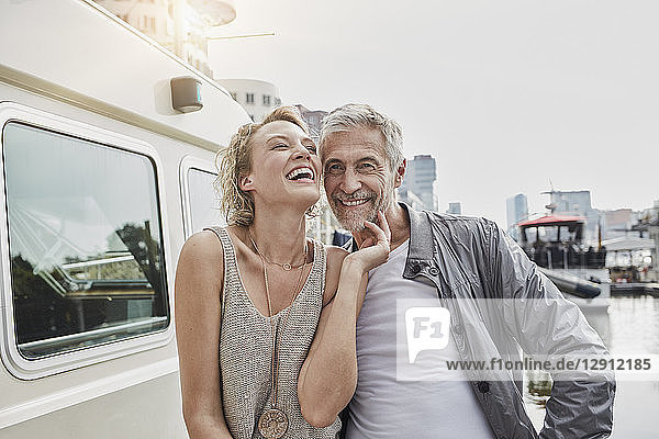 Happy older man and young woman on jetty next to yacht