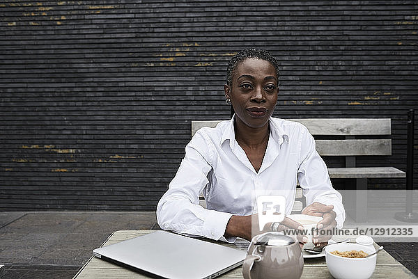 Portrait of businesswoman sitting on terrace of a coffee shop drinking tea