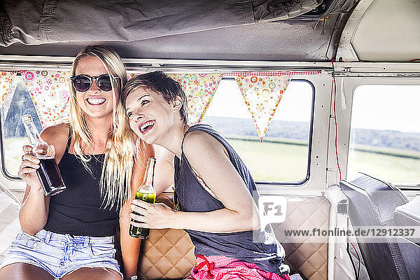 Two happy women inside van with bottles