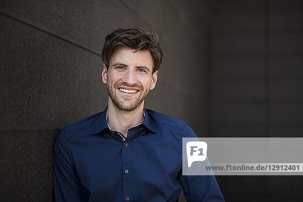 Portrait of smiling businessman at a wall