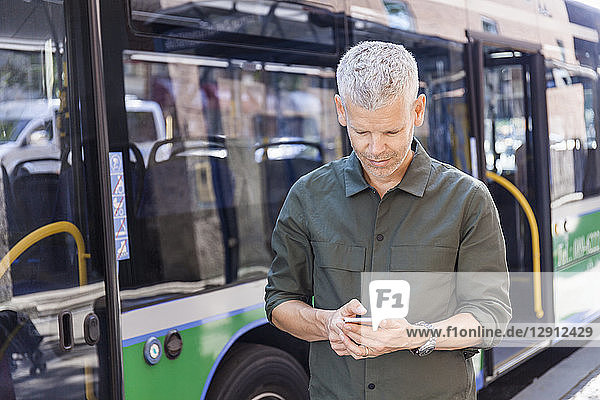 Mature man using cell phone in the city at a bus