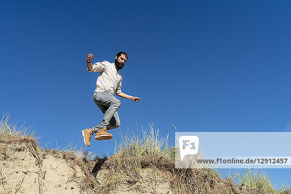 Young man jumping from a sand dune