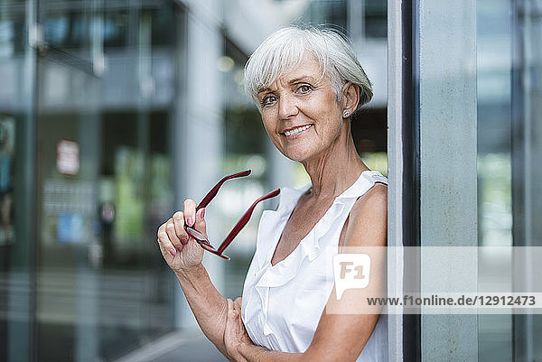 Portrait of smiling senior woman holding glasses