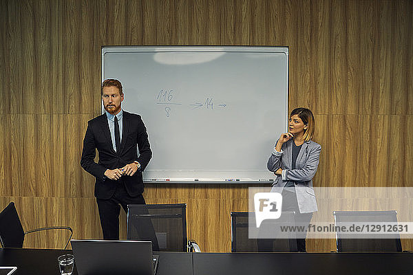 Businessman and businesswoman leading a presentation in boardroom