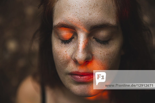 Portrait of young woman with freckles closing her eyes