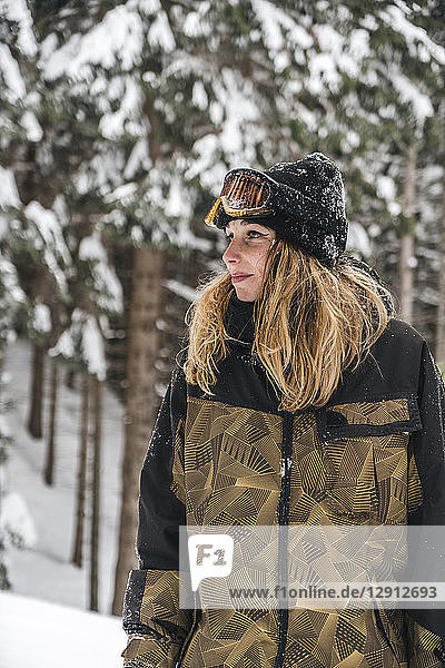 Young woman in skiwear in winter forest looking sideways