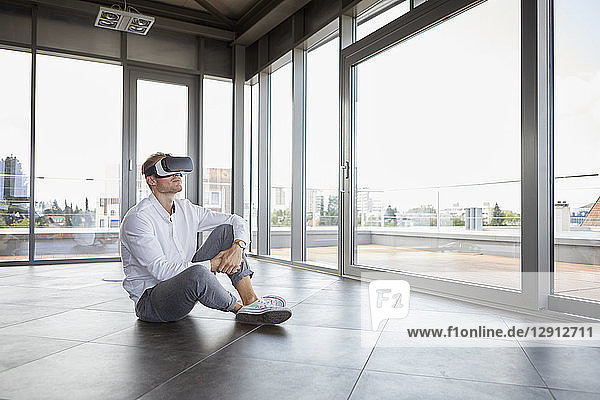 Businessman sitting in empty room wearing VR glasses