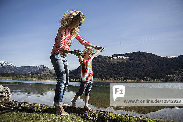 Austria  Tyrol  Walchsee  happy mother and daughter walking at the lake