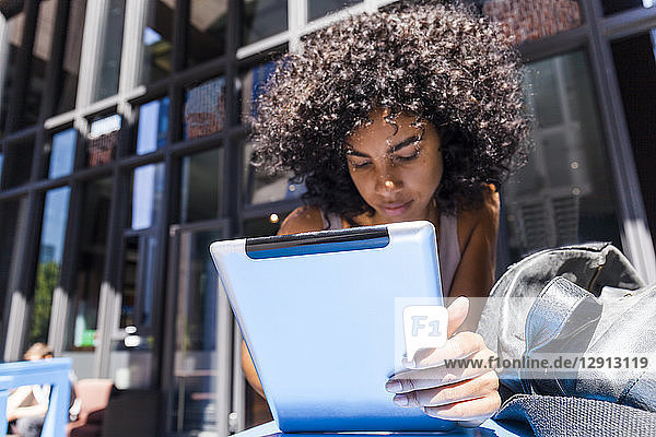 Young woman with curly using tablet in the city
