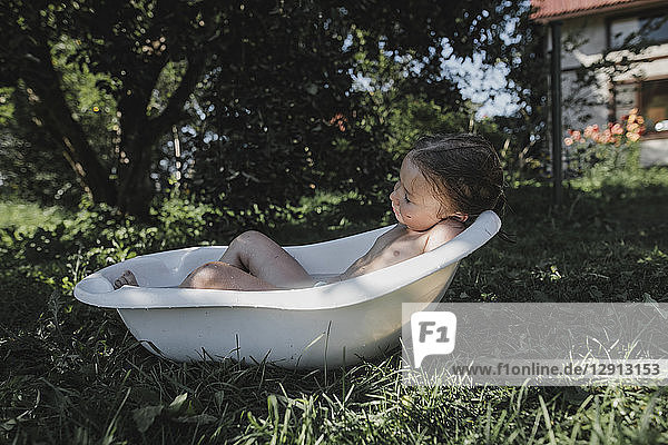 Little girl relaxing in bath tub in garden