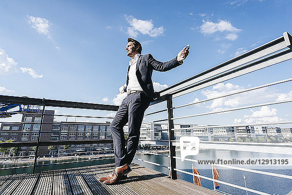 Happy businessman standing on balcony  with arms out