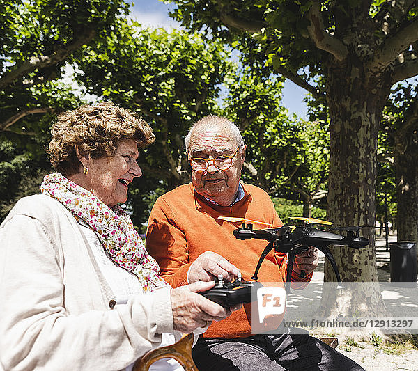 Senior couple playing with a drone in park