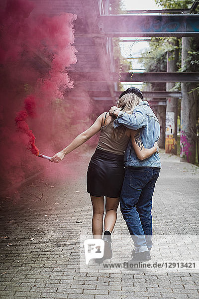 Young couple with smoke torch walking outdoors