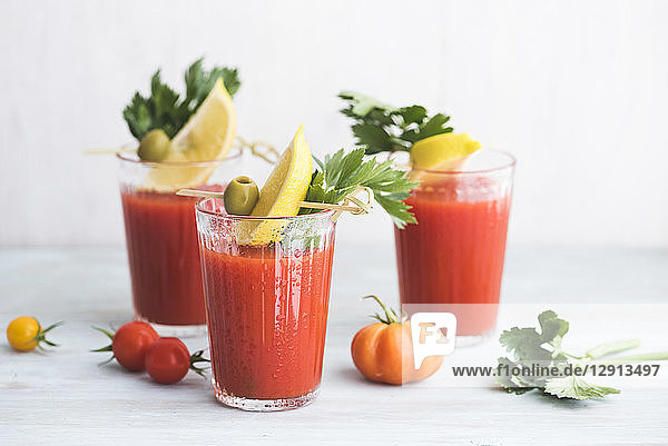 Glasses of fresh spicy tomato juice with cellery garnished with lemon slice  green olive and parsley