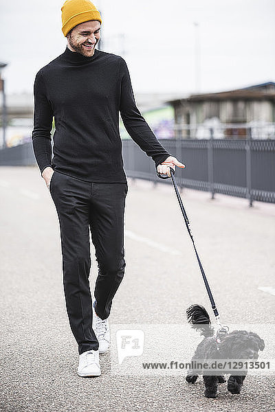 Fashionable young man walking with dog on a bridge