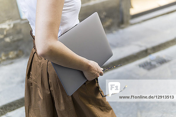 Close-up of woman carrying laptop outdoors