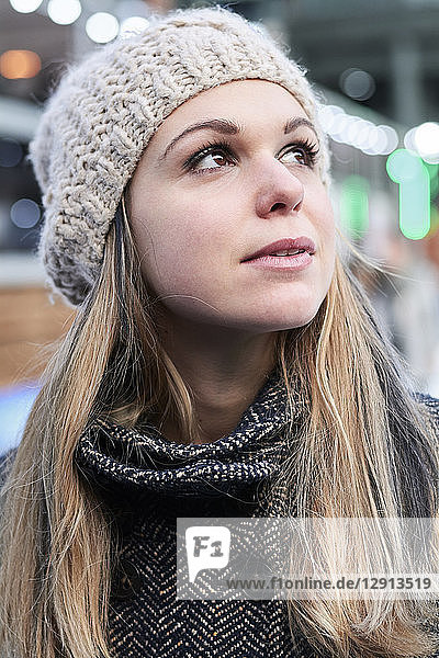 Portrait of pensive blond young woman wearing wool cap in winter