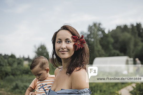 Portrait of mother with flower in her hair with baby in garden
