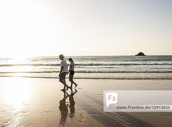 Young couple doing a romantic beach stroll at sunset