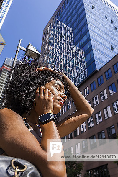 Germany  Frankfurt  portrait of young woman with smartwatch on the phone in front of skyscrapers