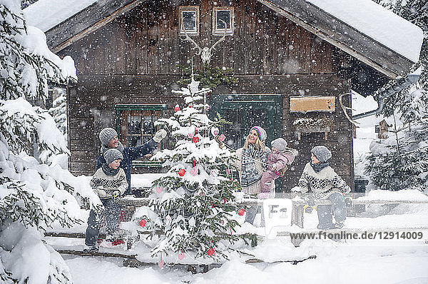 Austria  Altenmarkt-Zauchensee  family decorating Christmas tree at wooden house