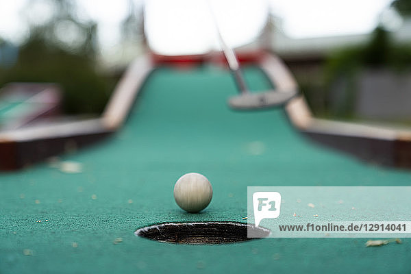 Ball and club playing miniature golf